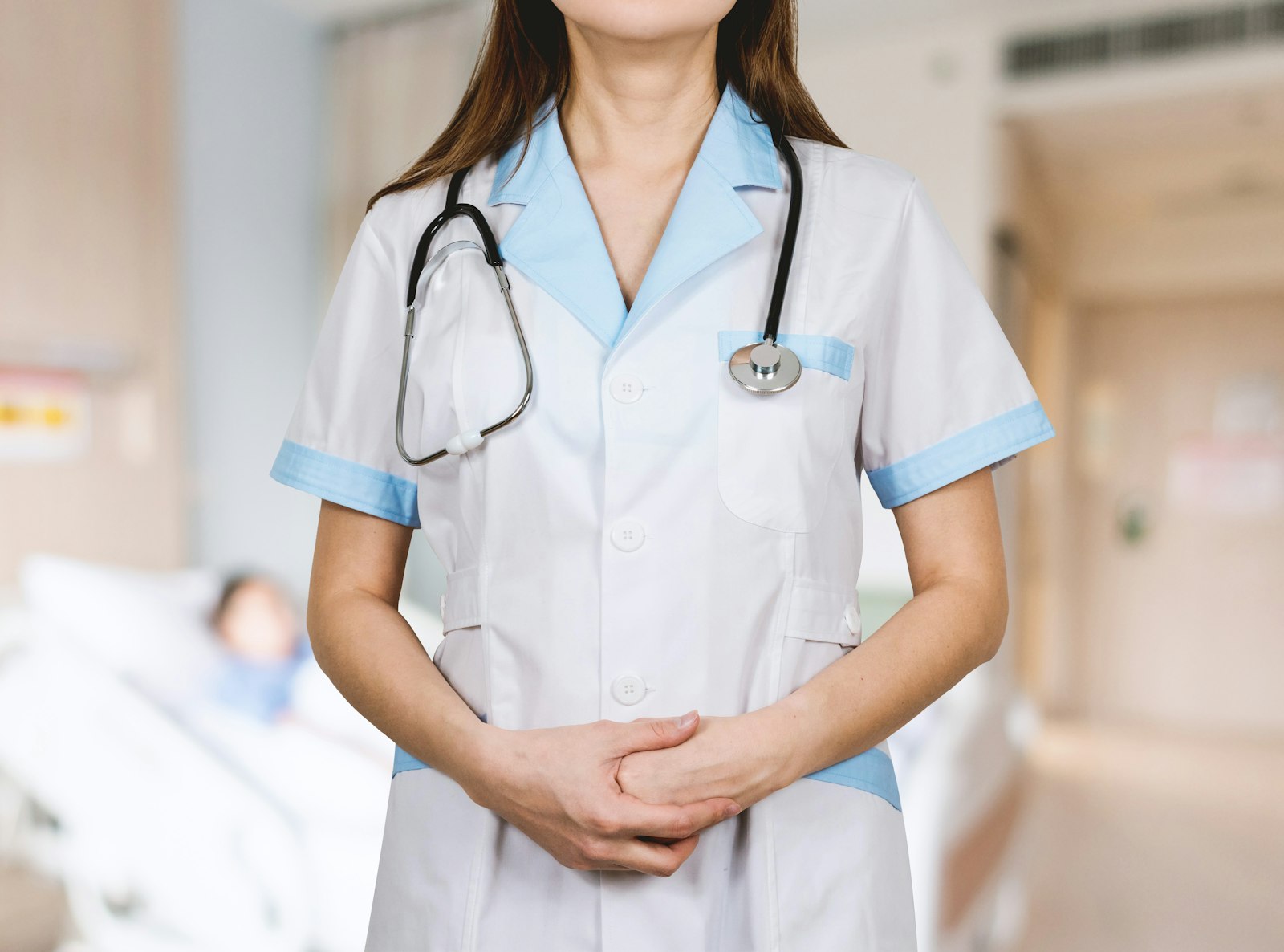 Profesional de la salud con bata blanca y estetoscopio en un pasillo hospitalario.
